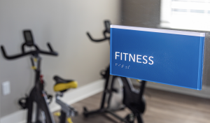 fitness center sign with braille for ada compliance.